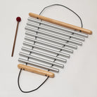 Metal chimes with wooden handles and a mallet on a light background